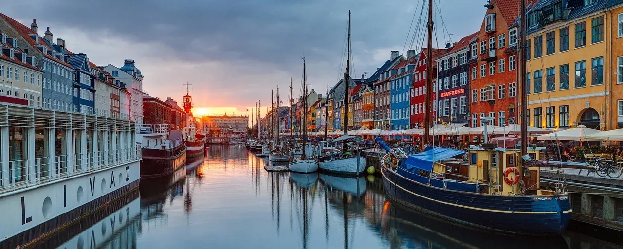 Colourful buildings and boats reflected in Nyhavn harbour, Copenhagen, at sunset
